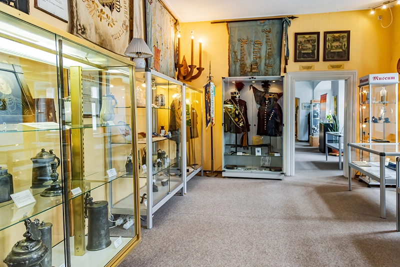 Ausstellungsraum mit Vitrinen mit alten Zinnkrügen, und Uniformen