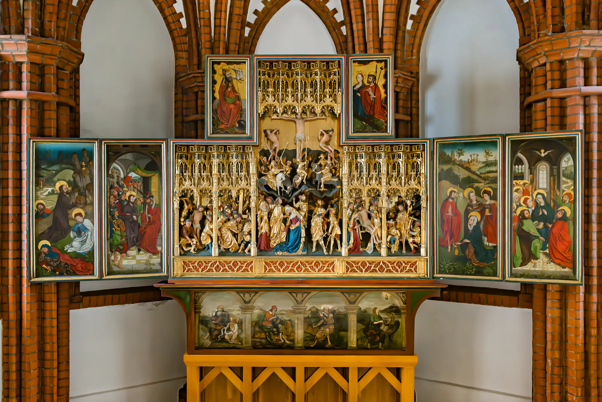 Altar mit geöffneten Flügeln. Im Inneren sind filigrane geschnitzte Figuren zu sehen